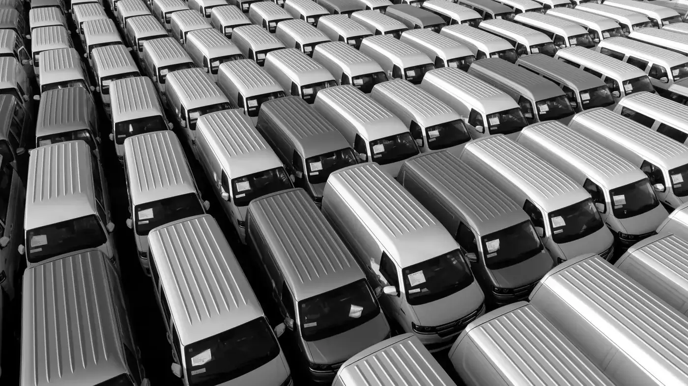 Luftaufnahme eines Fuhrparks: weiße Transporter in Reihen auf einem Parkplatz